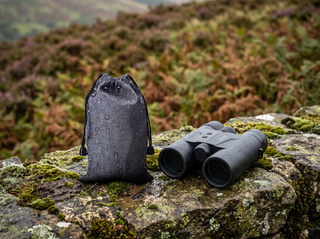 The kit on a mossy wall beside a pair of binoculars